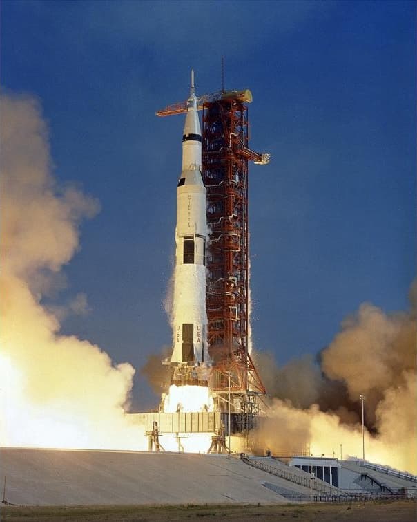 The Saturn V rocket carrying Apollo 11 lifts off from Pad 39A between billowing clouds of smoke and steam