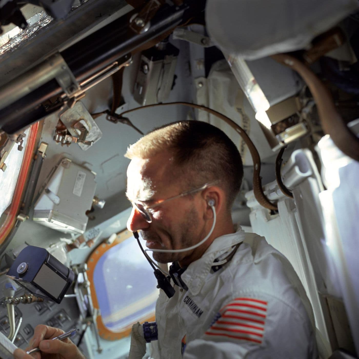 Velitel Wally Schirra v kabině lodi Apollo 7 na oběžné dráze — na skafandru čitelná jmenovka „W. Schirra" (NASA).