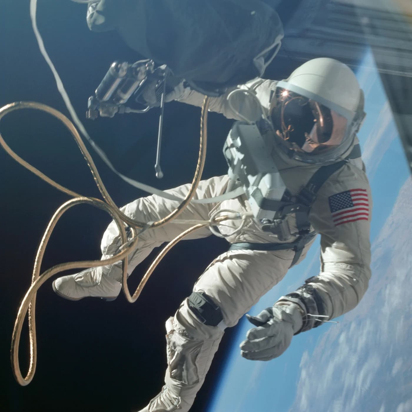 Edward H. White II floats outside Gemini 4 on 3 June 1965 during the first American spacewalk, attached by a gold-wrapped umbilical and holding a hand-held manoeuvring unit (Gemini 4, NASA, 1965).