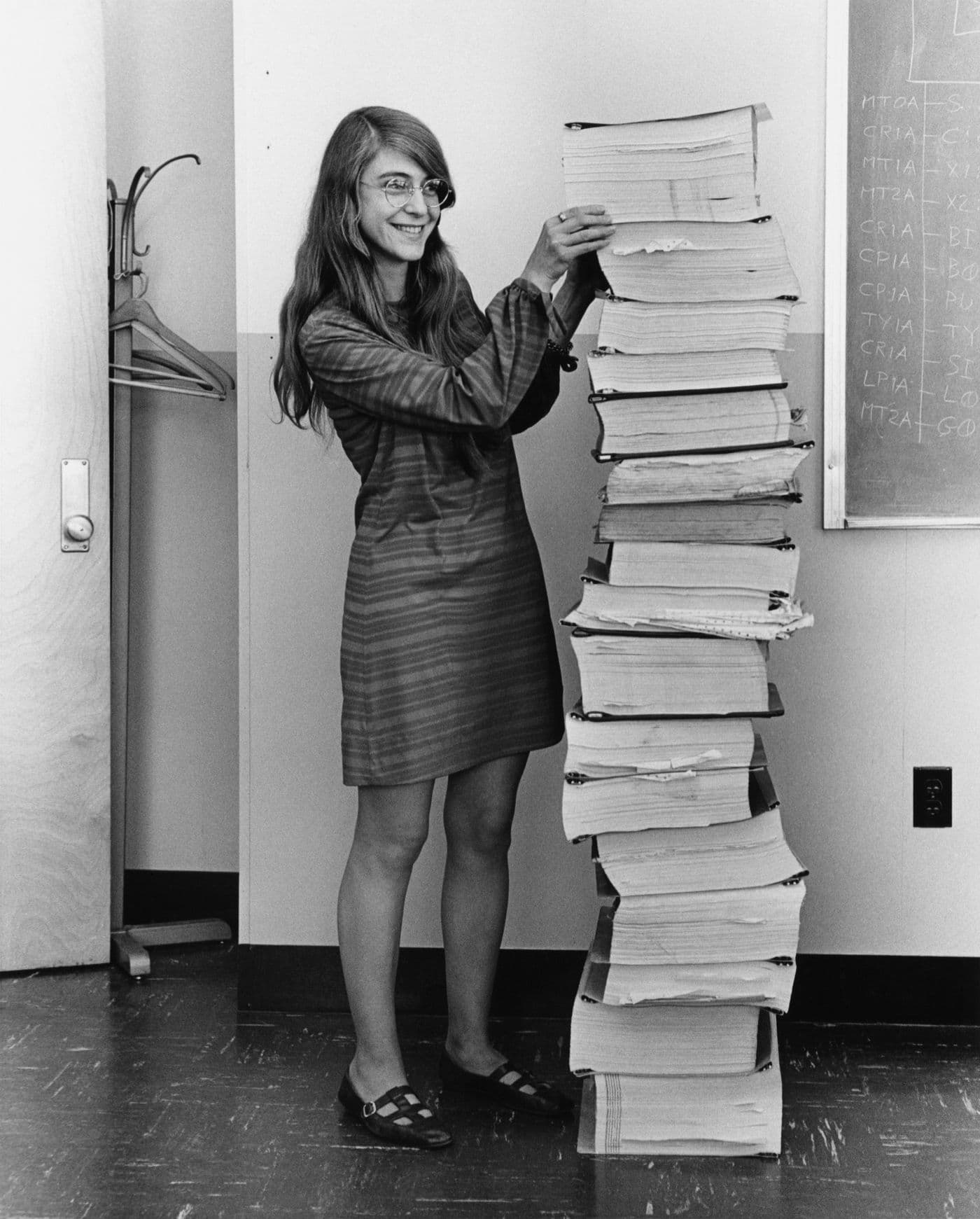 Margaret Hamilton standing beside a stack of Apollo flight software listings in 1969