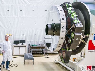 A NASA optical engineer inspects the surface of the Nancy Grace Roman telescope's primary mirror in a clean room.