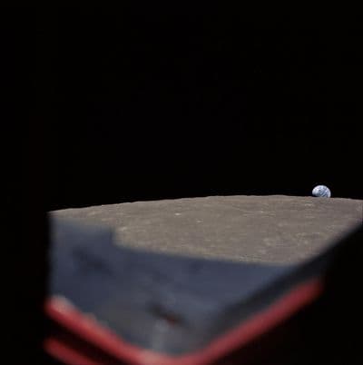 High-oblique view of Moon's surface showing earth rising above horizon