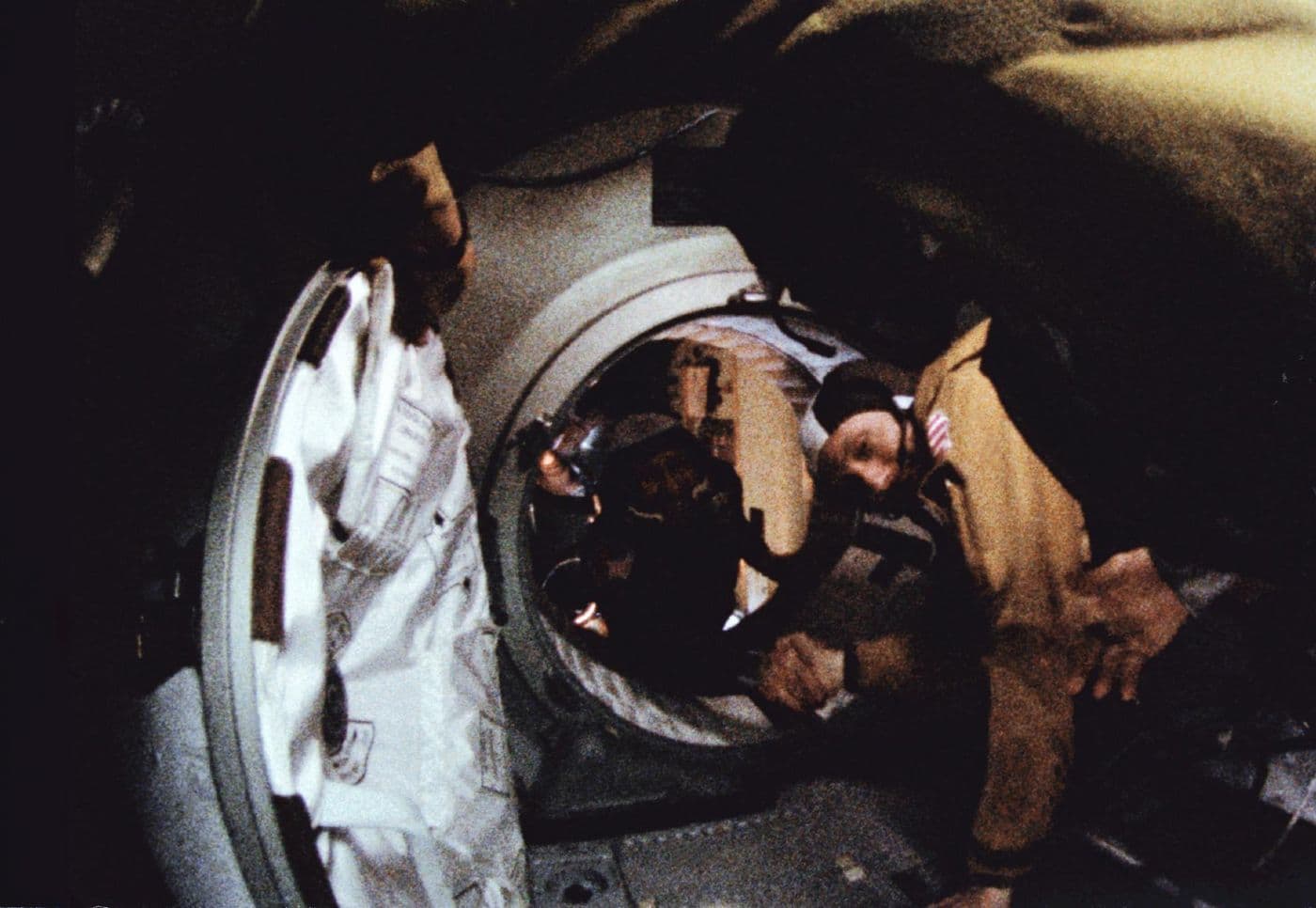Podání ruky ve vesmíru — astronaut a kosmonaut se setkávají v průlezu mezi loděmi Apollo a Sojuz.