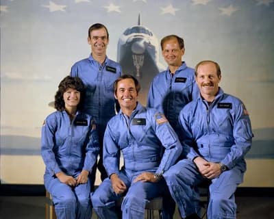 The STS-7 crew in March 1983. Sally Ride is seated at left, commander Robert Crippen at center and pilot Frederick Hauck at right; John Fabian and Norman Thagard stand behind them. NASA, S83-29016.