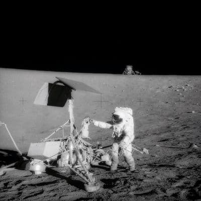 Astronaut u sondy Surveyor 3; na obzoru stojí lunární modul Intrepid — přistání jen ~160 m od sondy (NASA).